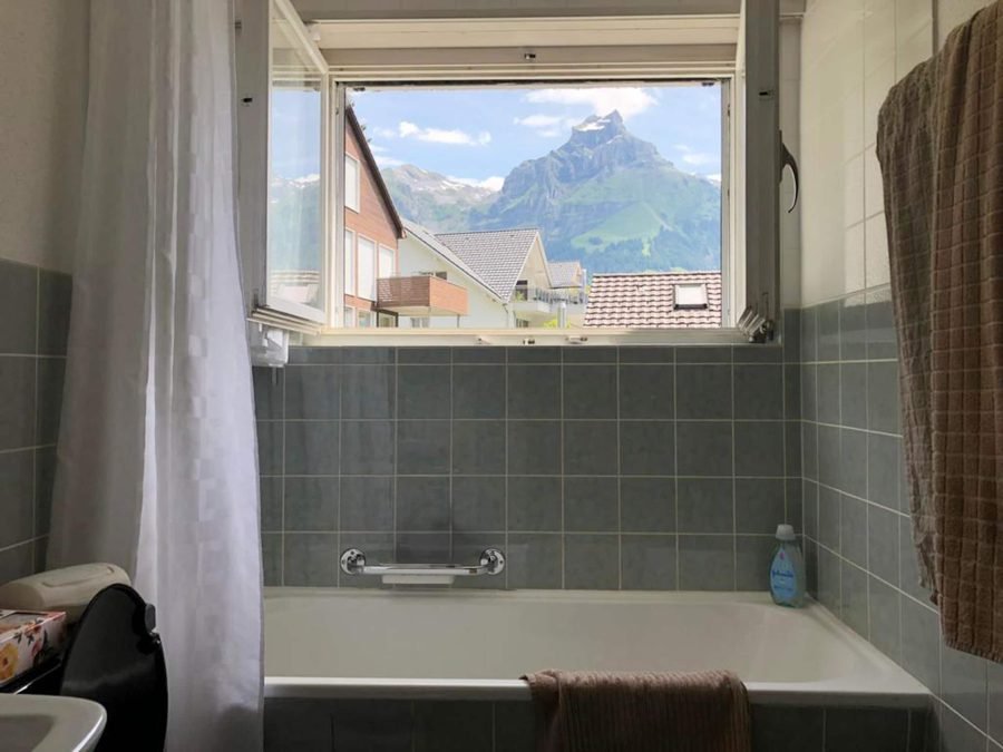 Bathtub beneath a window framing the peak of Hahnen