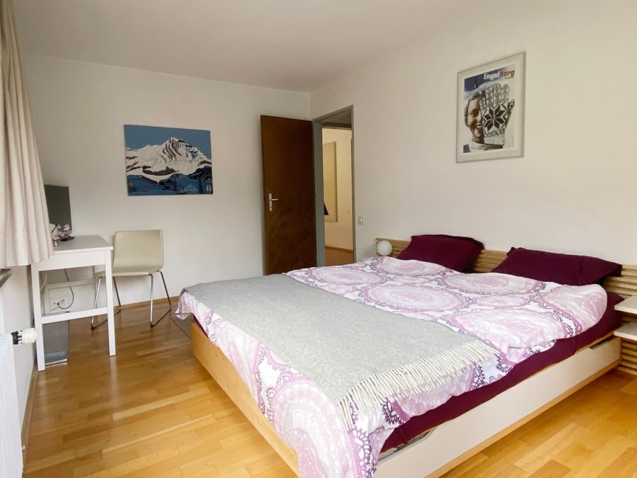 Bedroom with a double bed, oak floor and mountain prints on the walls