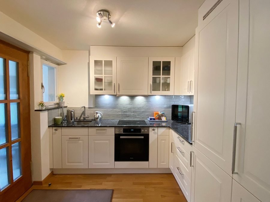 White fitted kitchen with granite worktop, oven, hob and dishwasher