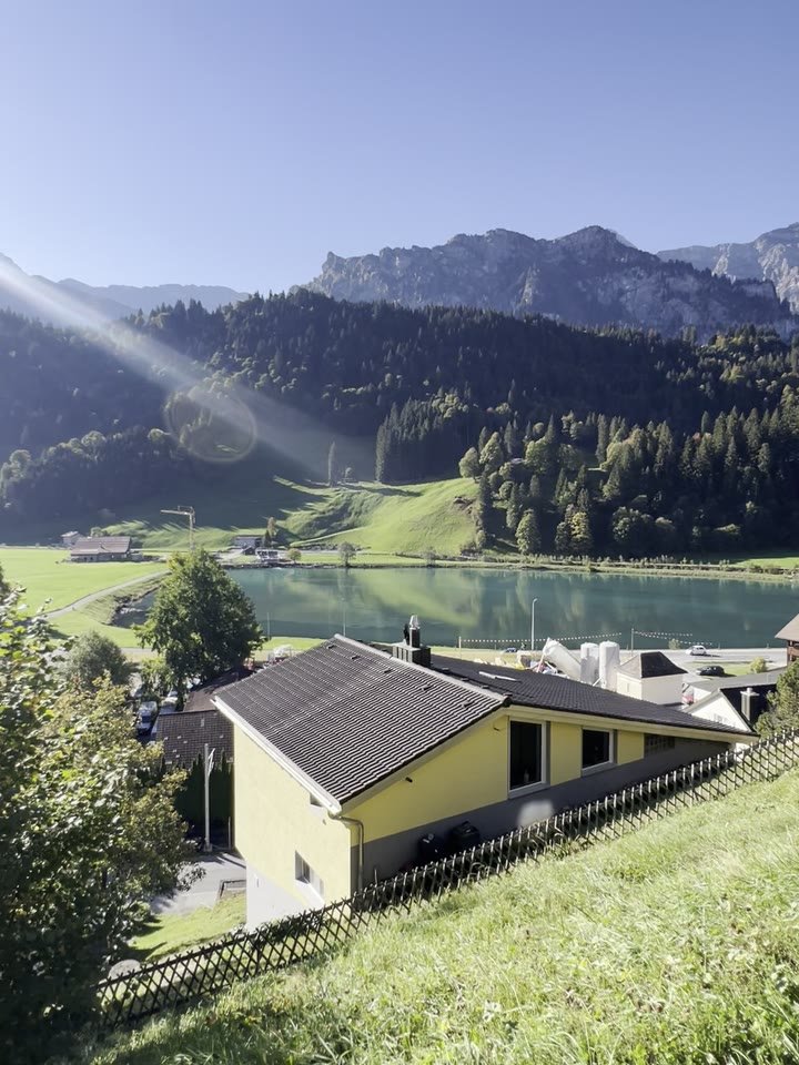 Looking out from the terrace door over the lawn to the Eugenisee and the mountains on a sunny morning